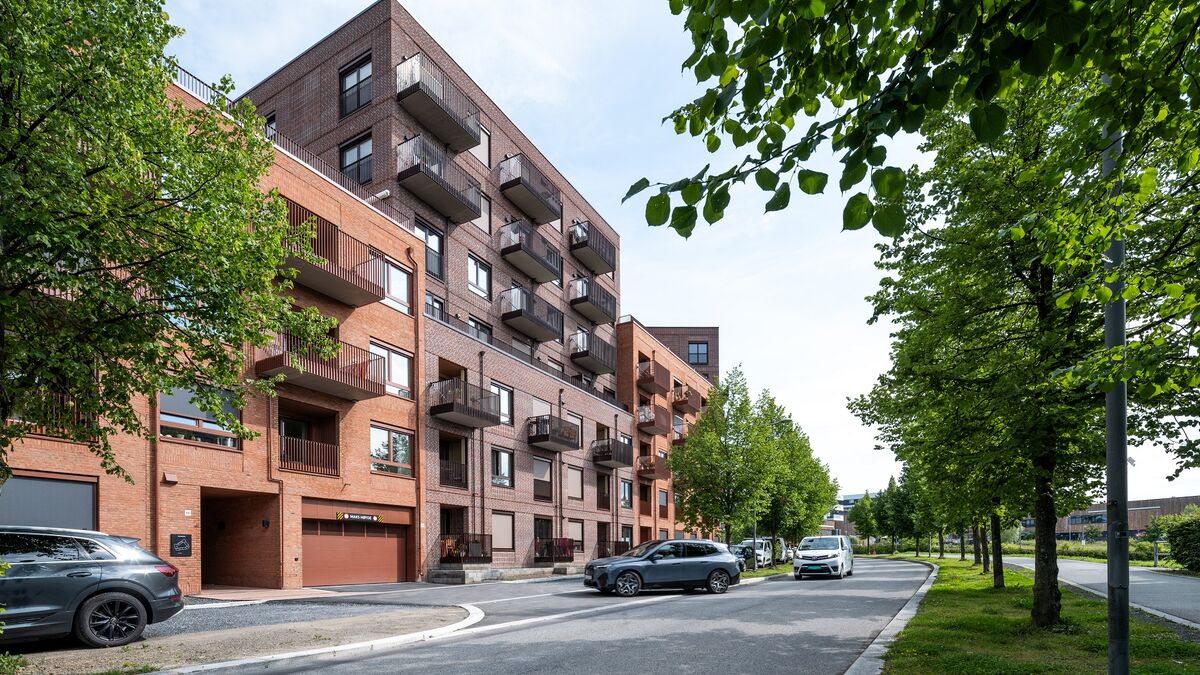 Moderne Wohnanlage, bei der ein Fahrzeug in eine Garage mit integriertem Parksystem fährt.