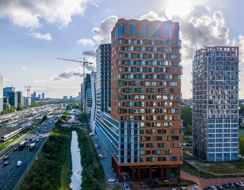 Vista esterna del progetto The Pulse ad Amsterdam con moderni grattacieli e infrastrutture di trasporto urbano.