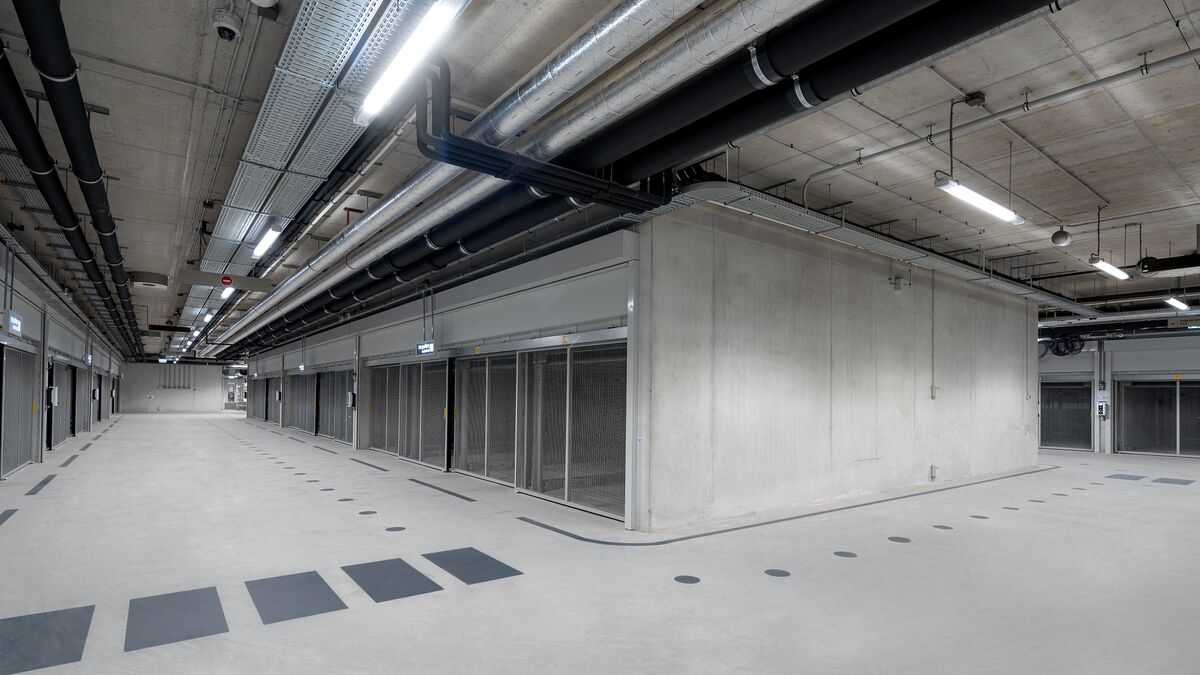 MModerna autorimessa sotterranea con area di incrocio, corsie di transito continue e sistemi di parcheggio disposti su entrambi i lati.