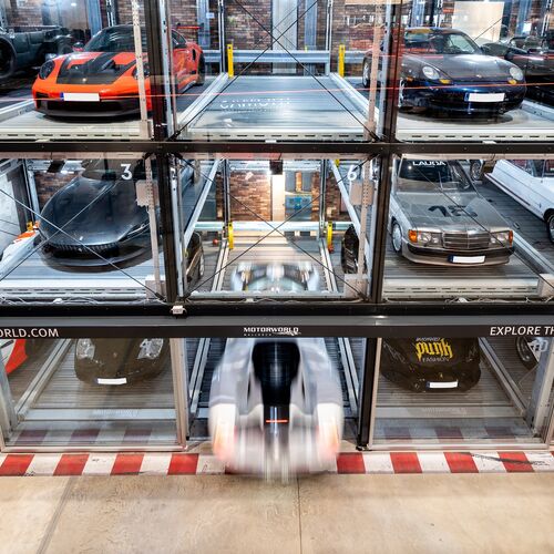 A parking system with several cars neatly lined up against a wall in the museum
