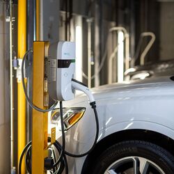 Un veicolo è parcheggiato sulla piattaforma di un sistema di parcheggio e viene ricaricato tramite la stazione di ricarica integrata per veicoli elettrici.