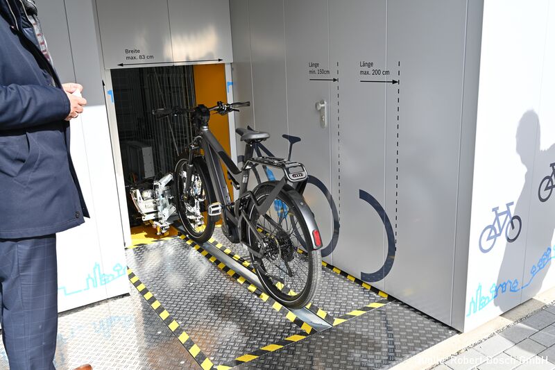 Fahrrad auf einer Radschiene vor einem automatischen Fahrradparksystem