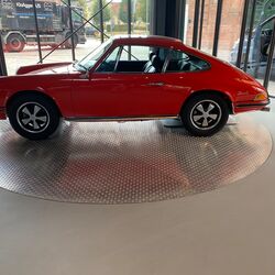 Une voiture rouge est posée sur une plate-forme tournante
