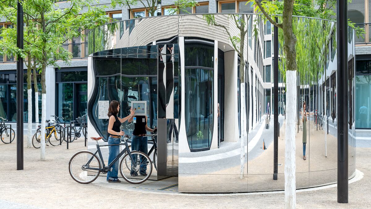Une femme à vélo utilise un écran sur le système de stationnement pour vélos