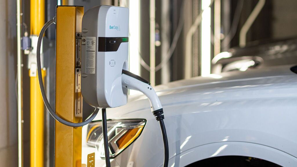 Un veicolo è parcheggiato sulla piattaforma di un sistema di parcheggio e viene ricaricato tramite la stazione di ricarica integrata per veicoli elettrici.