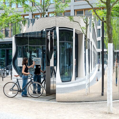 Frau mit Fahrrad bedient einen Monitor am Fahrradparksystem
