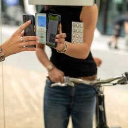 Une femme à vélo scanne un code QR sur le système de stationnement pour vélos