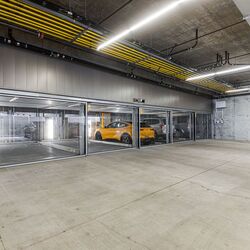 L'immagine mostra un moderno parcheggio sotterraneo con diversi posti auto vetrati di un sistema di parcheggio.