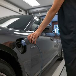 Frau steckt einen E-Ladestecker in das Auto
