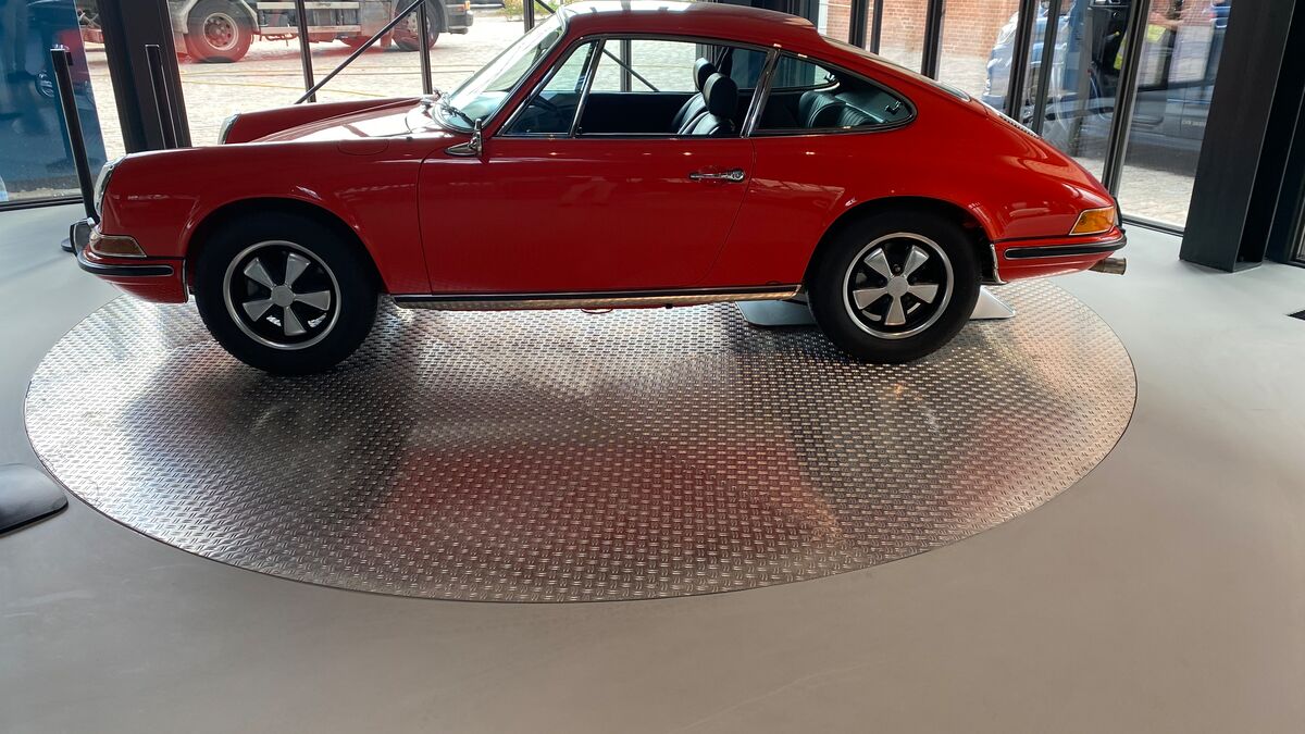 Une voiture rouge est posée sur une plate-forme tournante