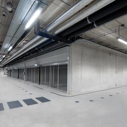 MModerna autorimessa sotterranea con area di incrocio, corsie di transito continue e sistemi di parcheggio disposti su entrambi i lati.