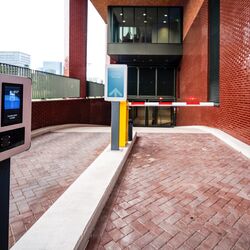 Ingresso a un moderno sistema di parcheggio con terminale di accesso, sistema di guida digitale e barriera automatica.