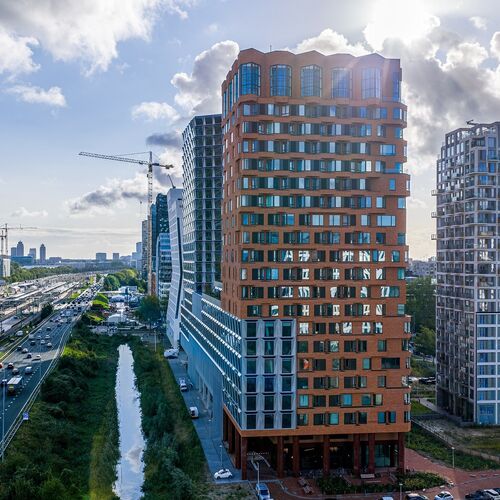 Vista esterna del progetto The Pulse ad Amsterdam con moderni grattacieli e infrastrutture di trasporto urbano.