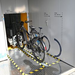 Bicycle on a guide rail in front of an automatic bicycle parking system