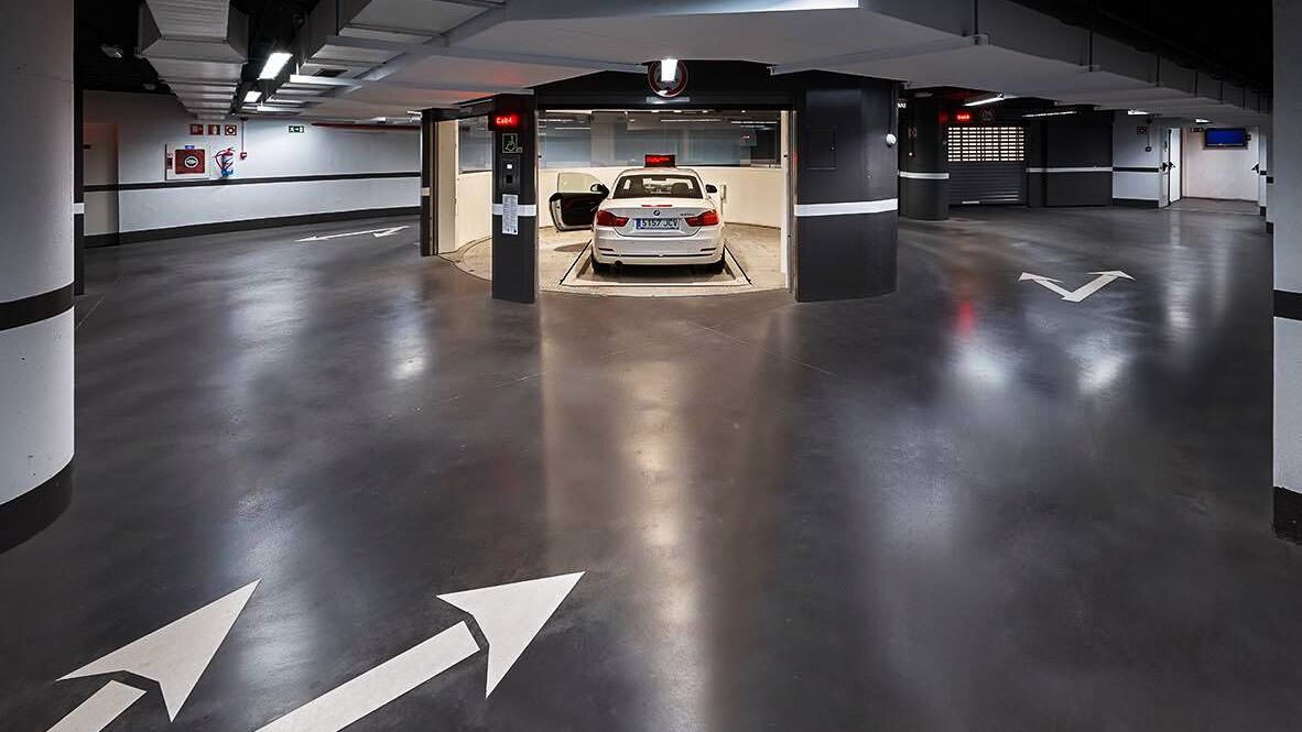 La voiture est garée dans une cabine d'entrée, sur une dalle de stationnement