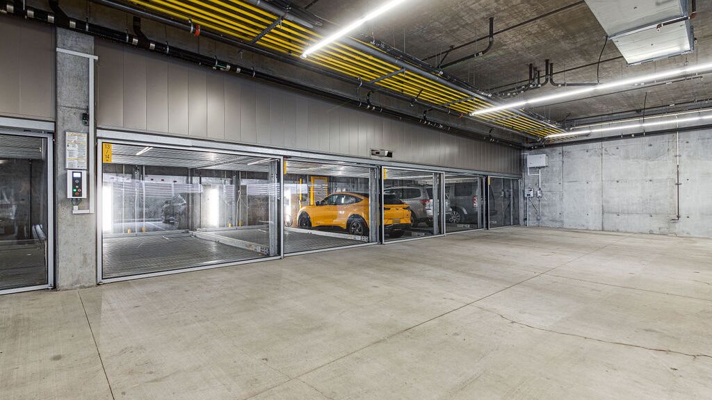 L'immagine mostra un moderno parcheggio sotterraneo con diversi posti auto vetrati di un sistema di parcheggio.